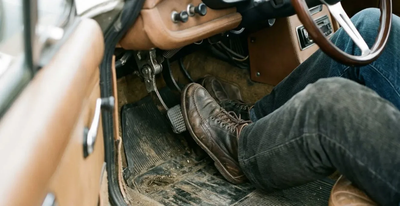 Vue du pédalier d'une voiture de collection avec pied sur la pédale d'embrayage